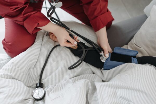 A medical professional checking a patient's blood pressure using a sphygmomanometer in a cozy setting.